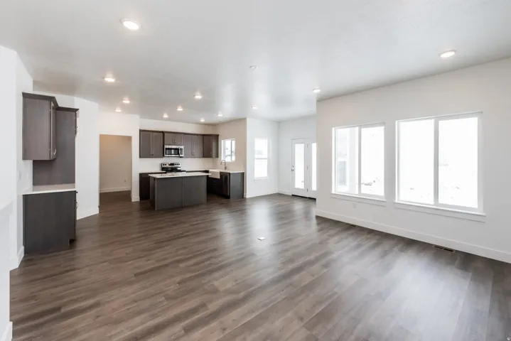 Kitchen with open floor plan, a center island, dark wood finish cabinets, light countertops, and dark wood-style floors
