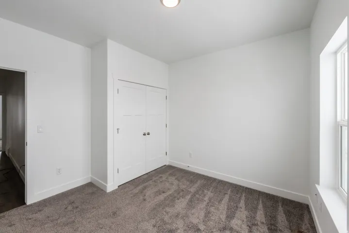 Unfurnished bedroom with dark carpet and a closet