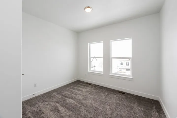 Unfurnished room with baseboards and dark carpet