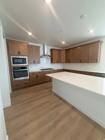 Kitchen featuring light wood-style flooring, stainless steel appliances, tasteful backsplash, light stone counters, and recessed lighting