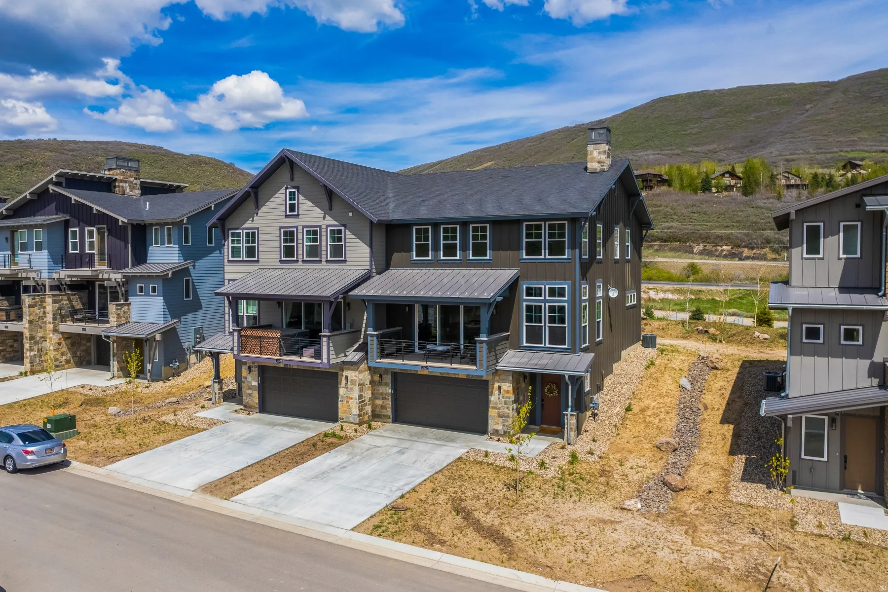 View of front facade featuring a mountain view, driveway, a chimney, an attached garage, and stone siding