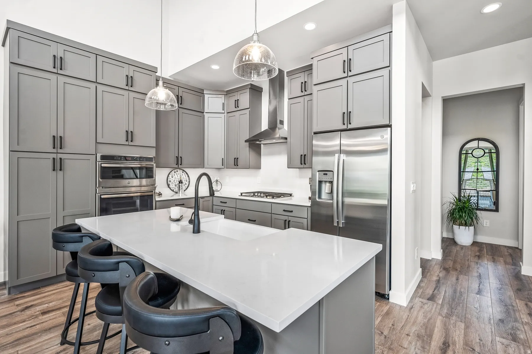 Kitchen featuring gray cabinets, stainless steel appliances, a center island with sink, and dark wood-style flooring