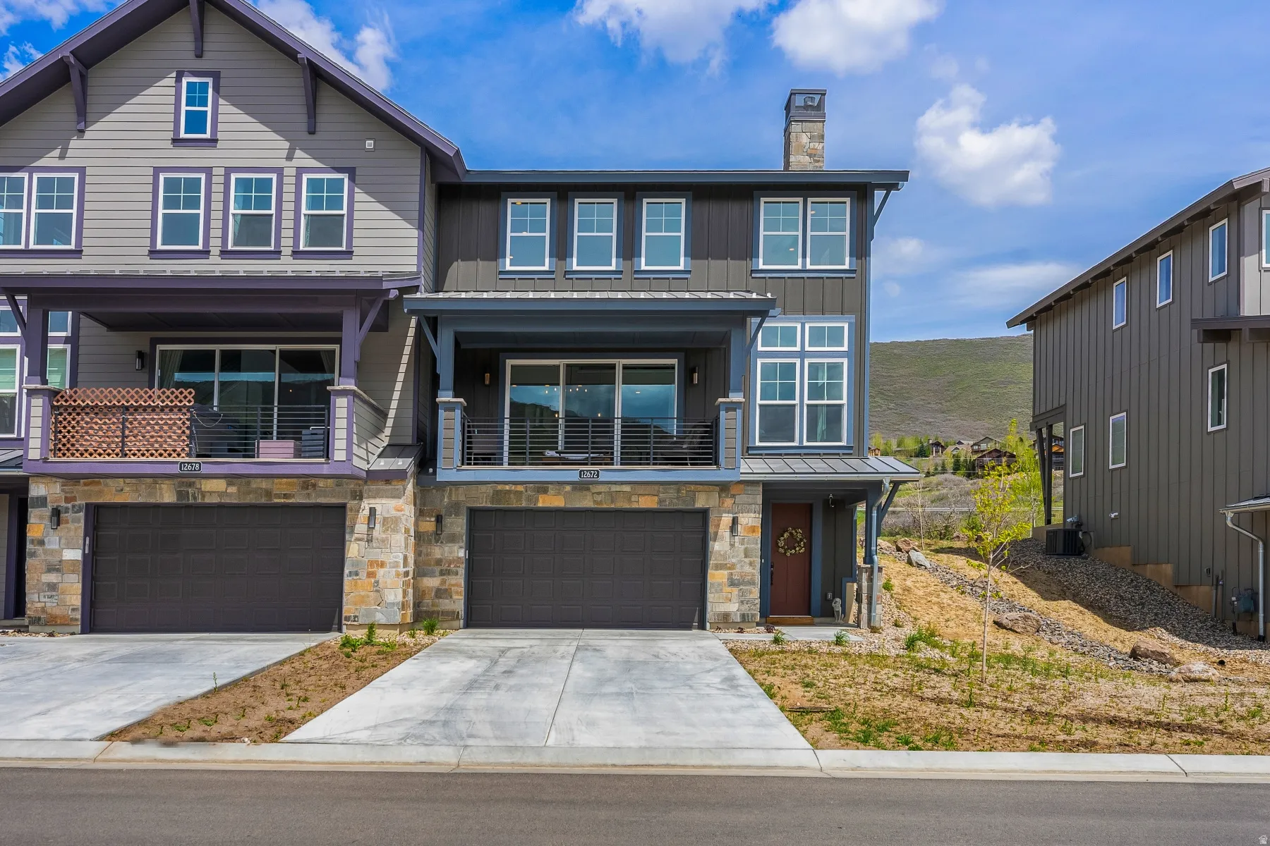 View of front of property featuring concrete driveway, board and batten siding, an attached garage, a chimney, and stone siding