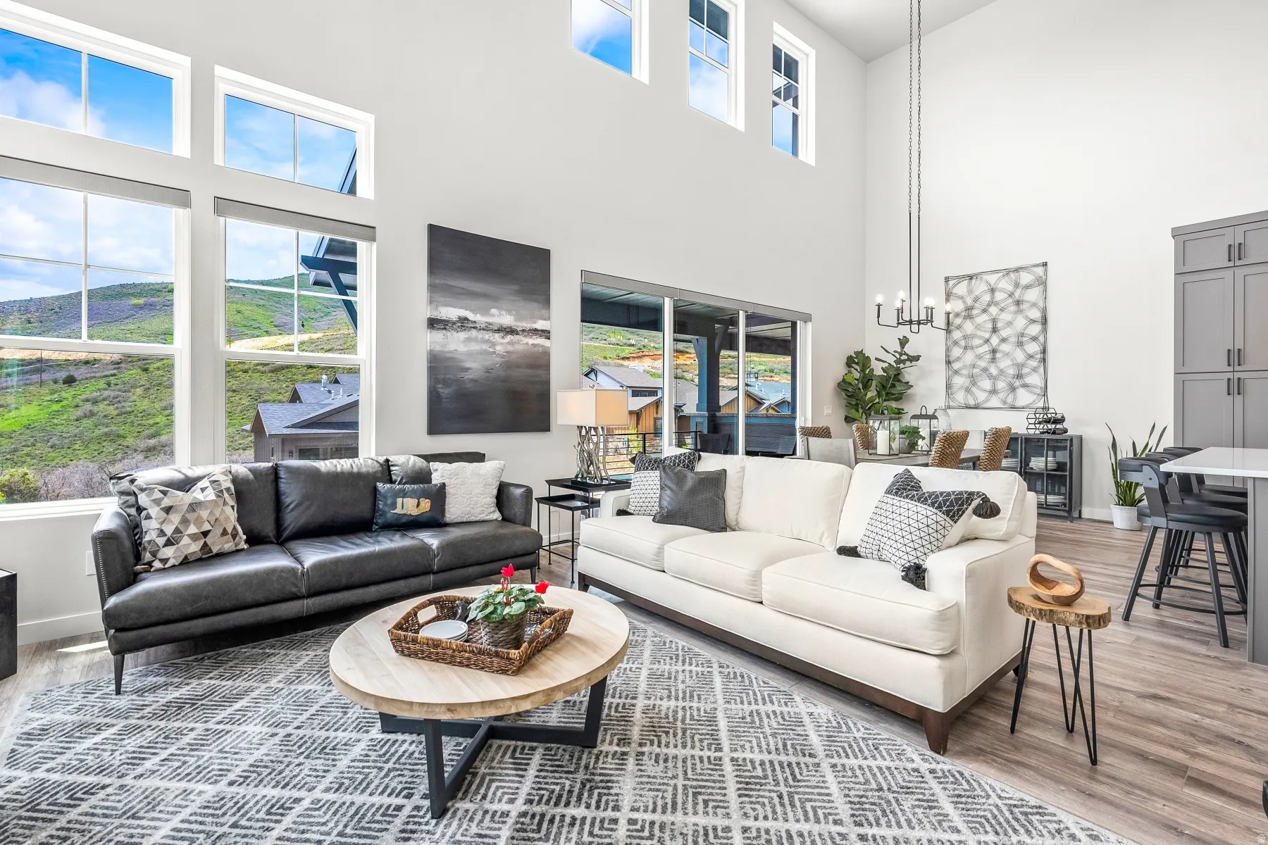 Living area featuring light wood finished floors, hanging lights, a high ceiling, and plenty of natural light