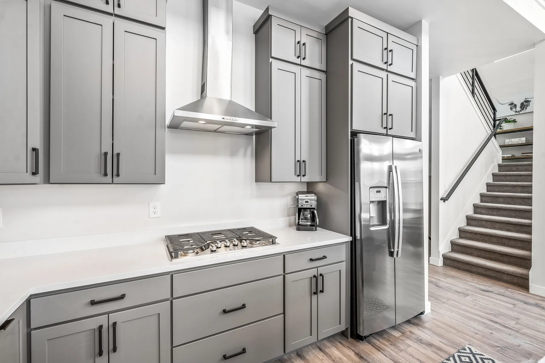 Kitchen featuring gray cabinetry, stainless steel appliances, light wood finished floors, and light stone counters