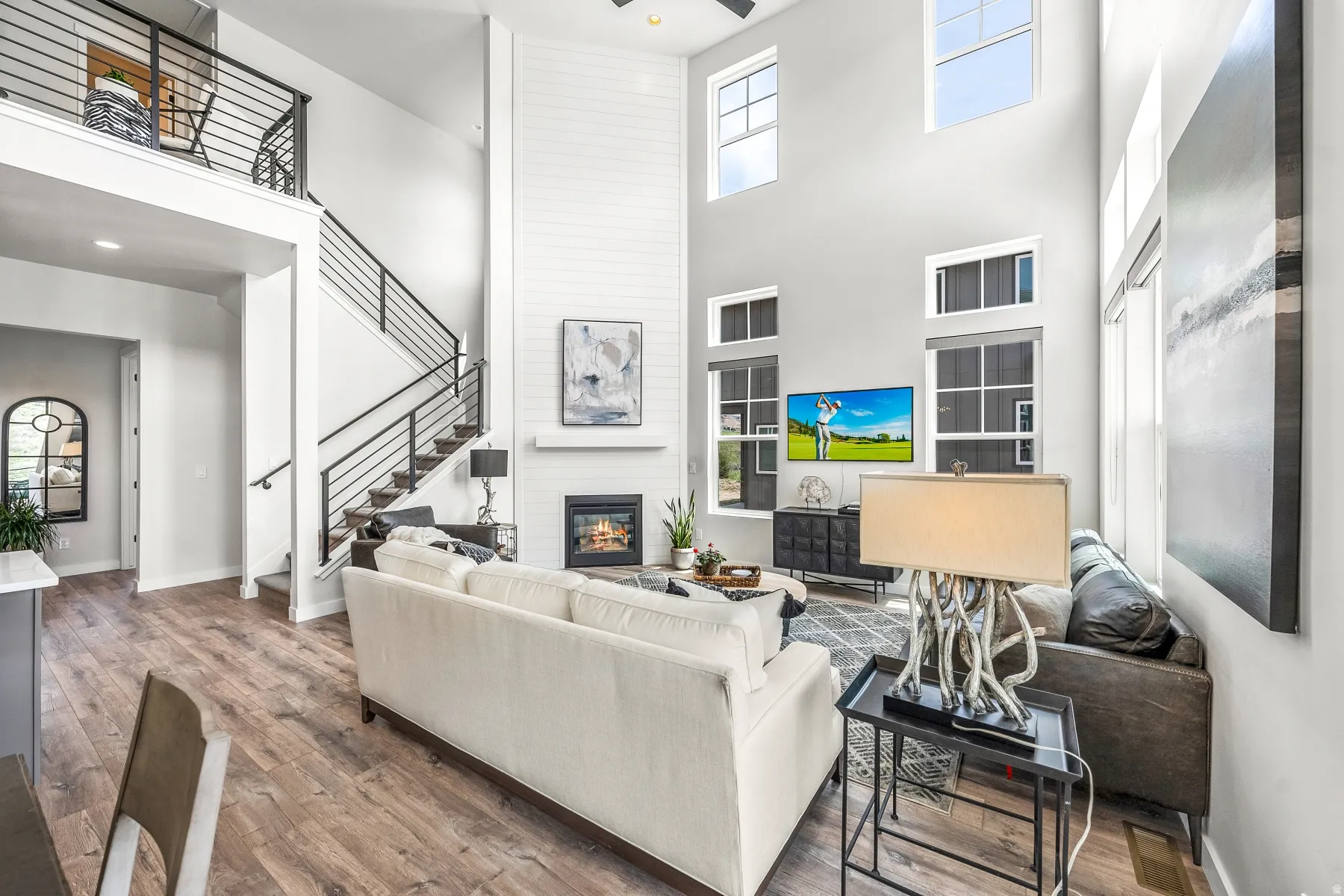 Living room featuring a large fireplace, hardwood / wood-style flooring, a high ceiling, and a ceiling fan