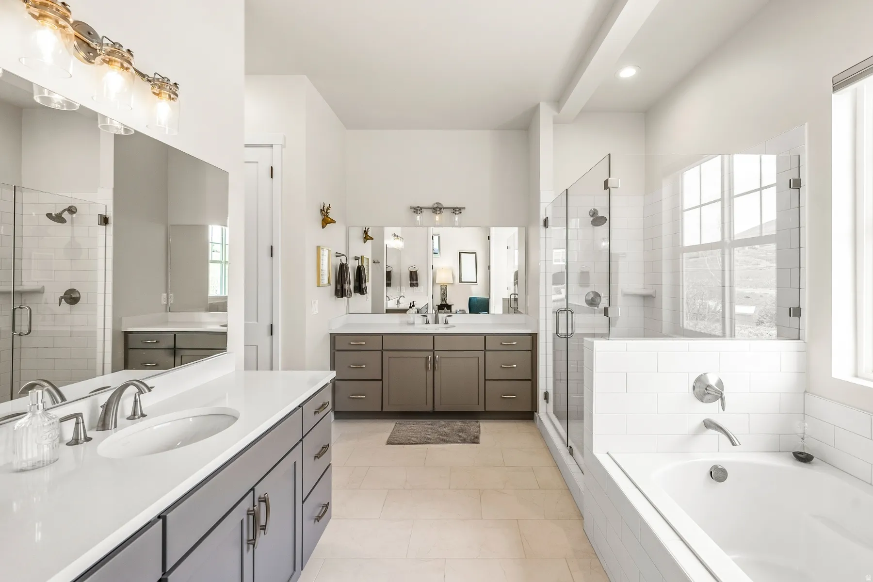 Bathroom featuring a shower stall, a bath, two vanities, and light tile patterned flooring