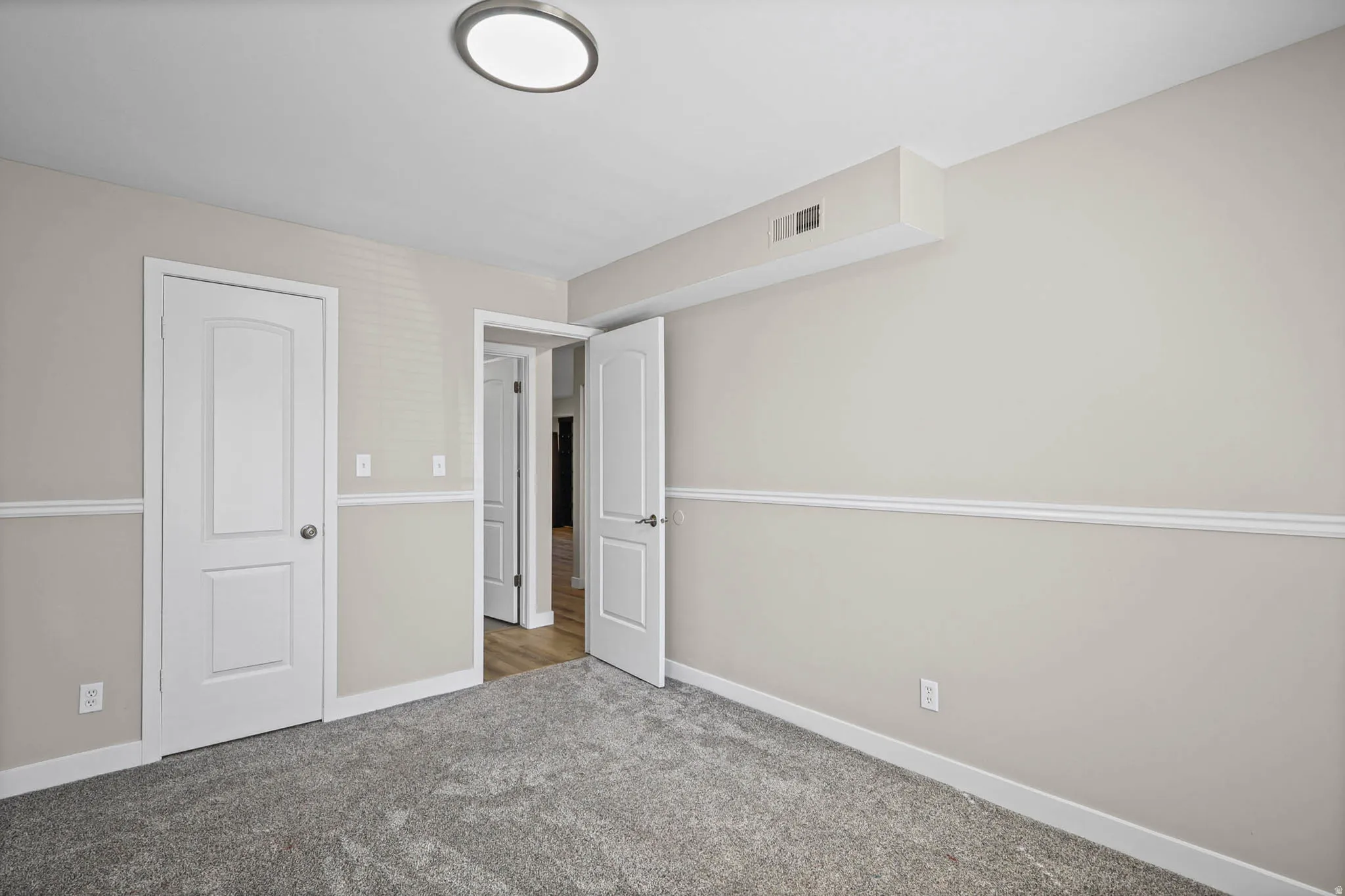 Unfurnished bedroom featuring light carpet and baseboards