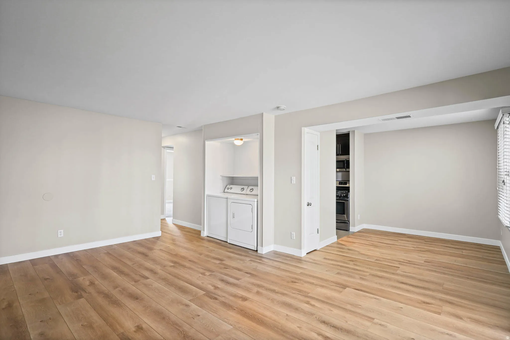Unfurnished living room featuring washing machine and dryer and light wood-type flooring