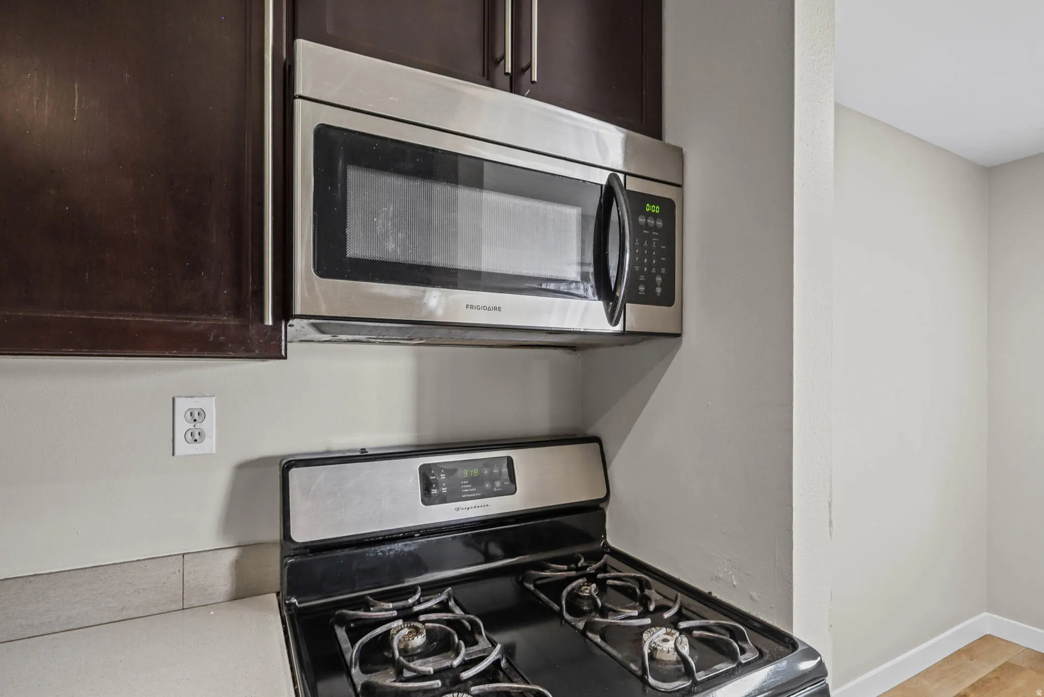 Kitchen view of stainless steel appliances, dark wood finish cabinetry, and light countertops