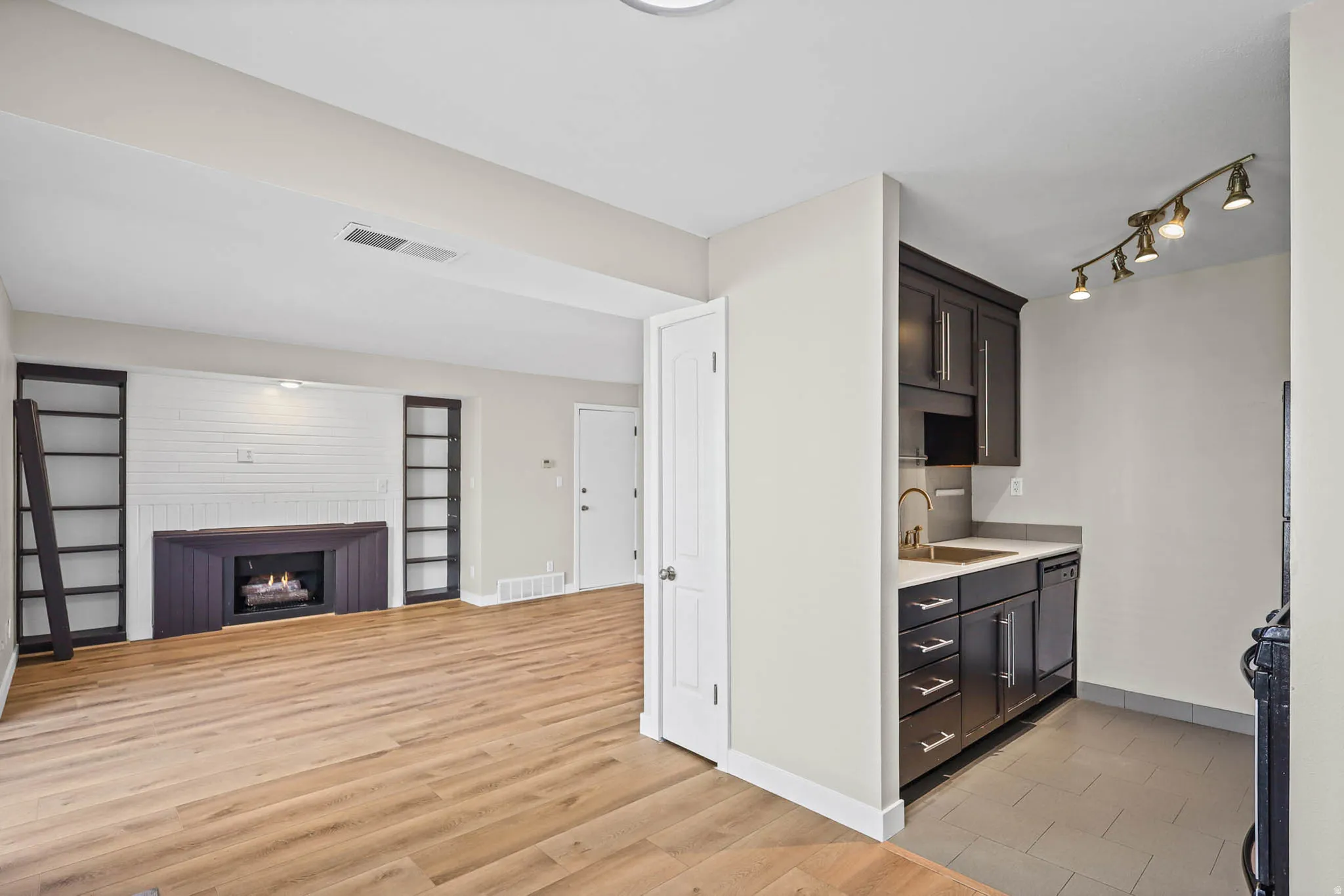 Kitchen featuring open floor plan, light wood-style flooring, black range, a lit fireplace, and dishwasher