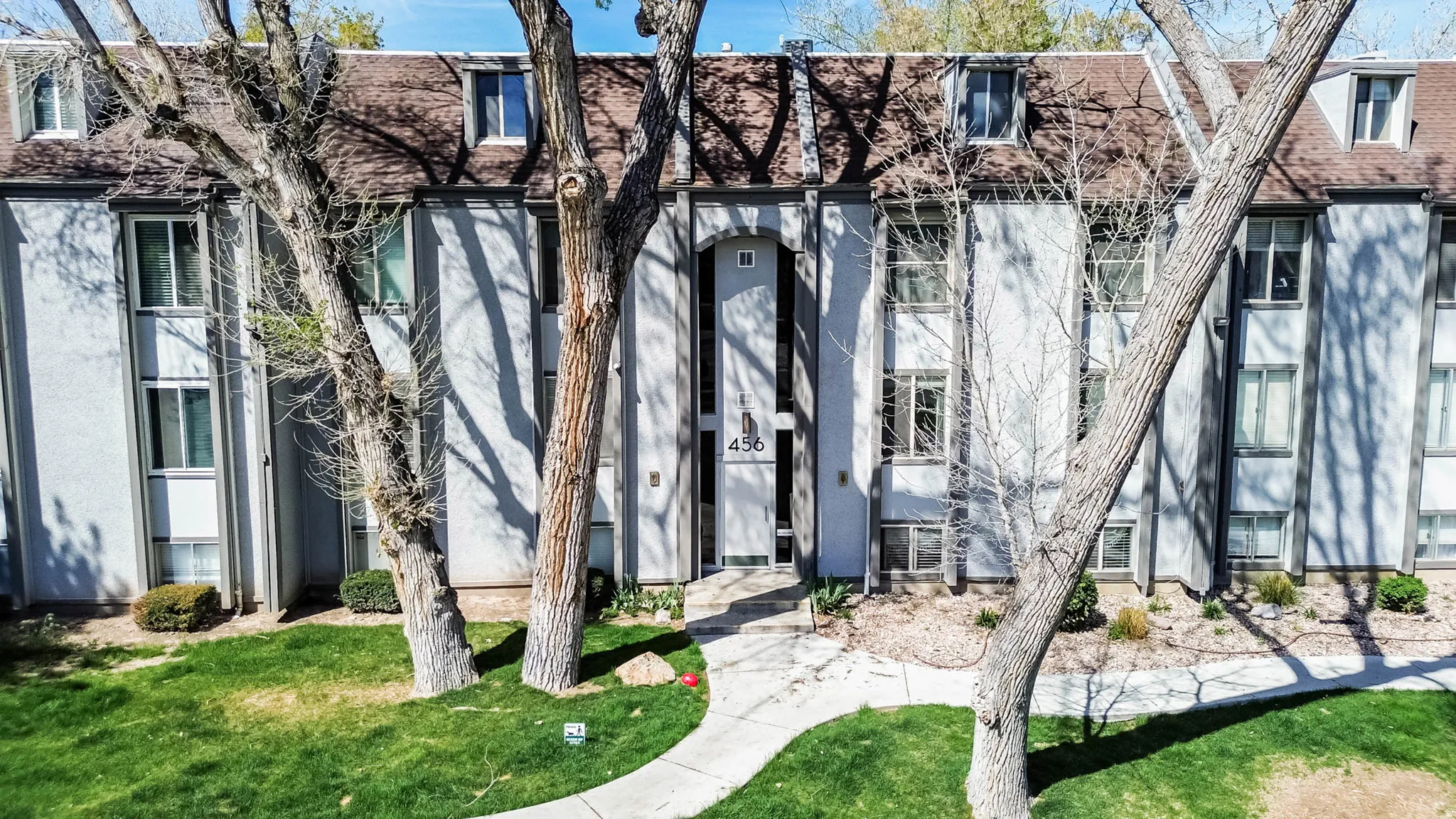 View of front of home with a shingled roof, a front yard, and stucco siding