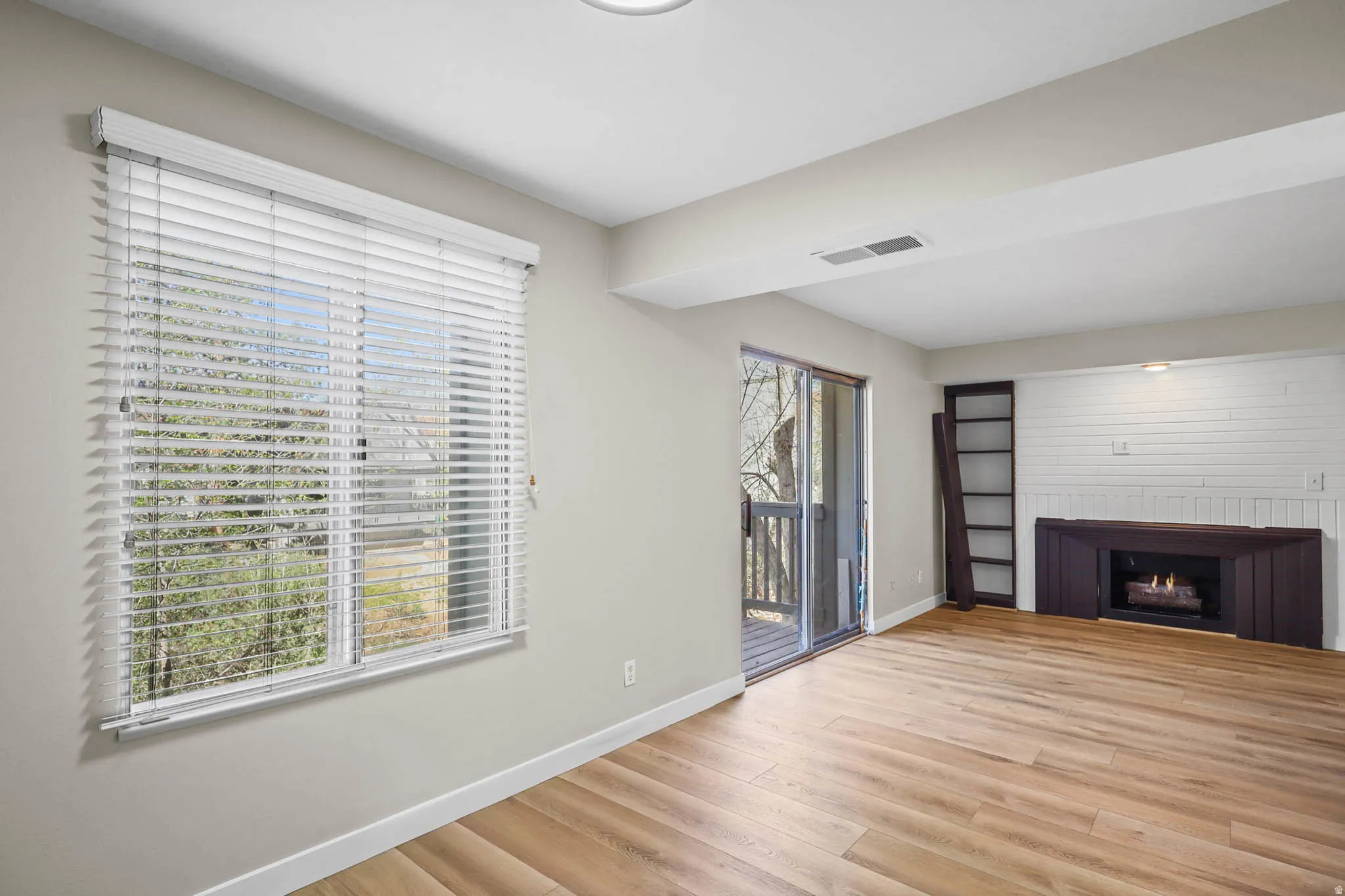 Unfurnished living room featuring light wood-type flooring and a lit fireplace