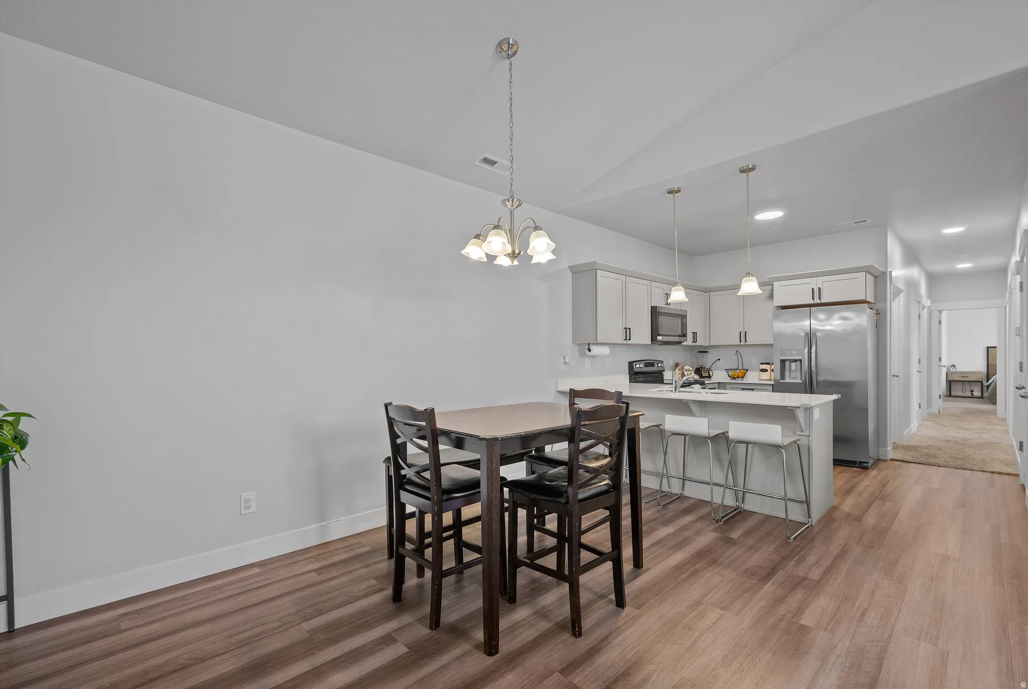Dining space with hanging lights, vaulted ceiling, and light wood-style flooring