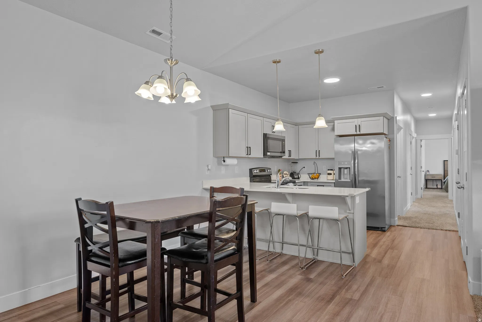 Dining area with suspended lighting and light wood-style floors