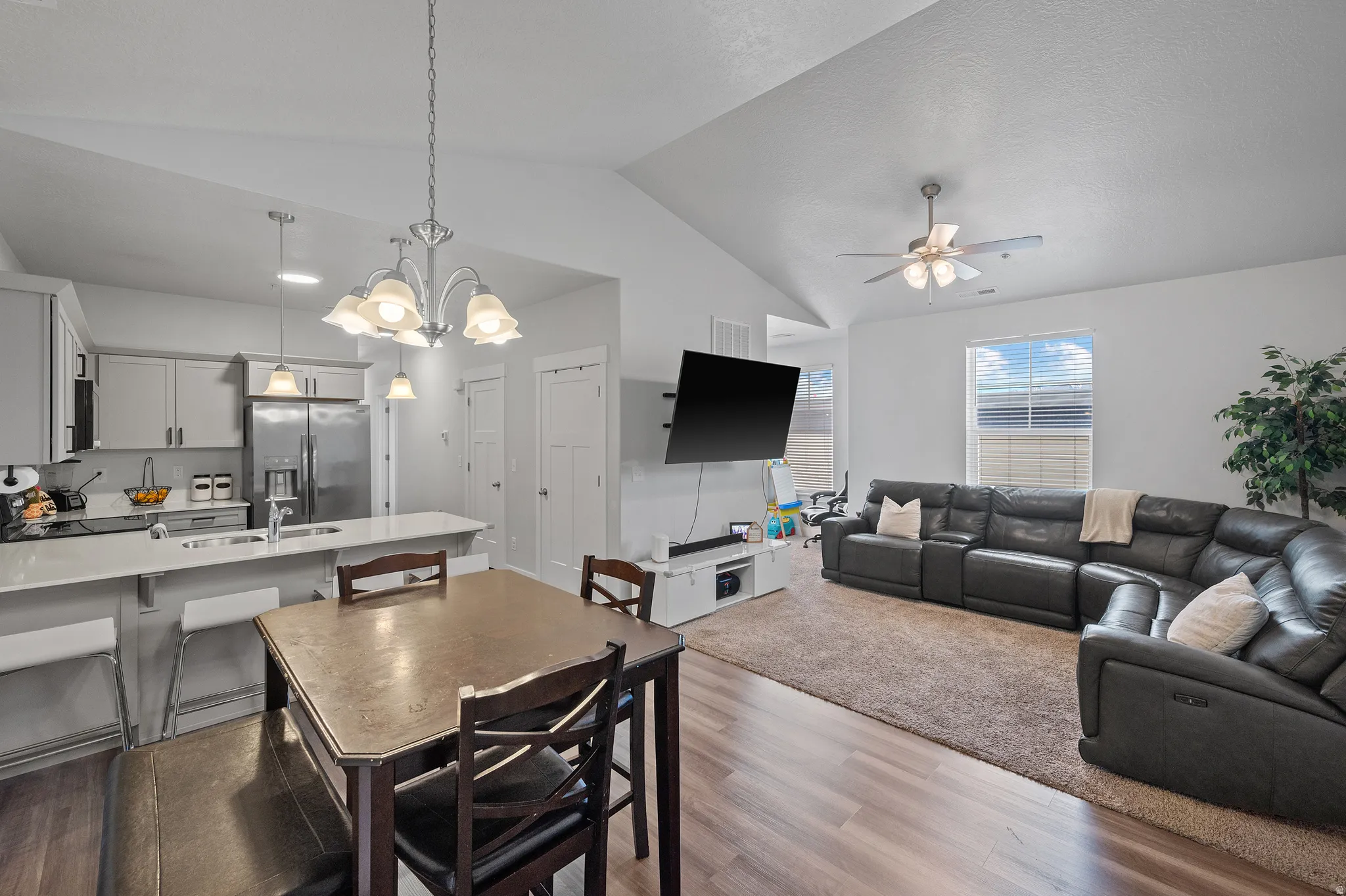 Dining space with a chandelier, lofted ceiling, light wood-style floors, and ceiling fan
