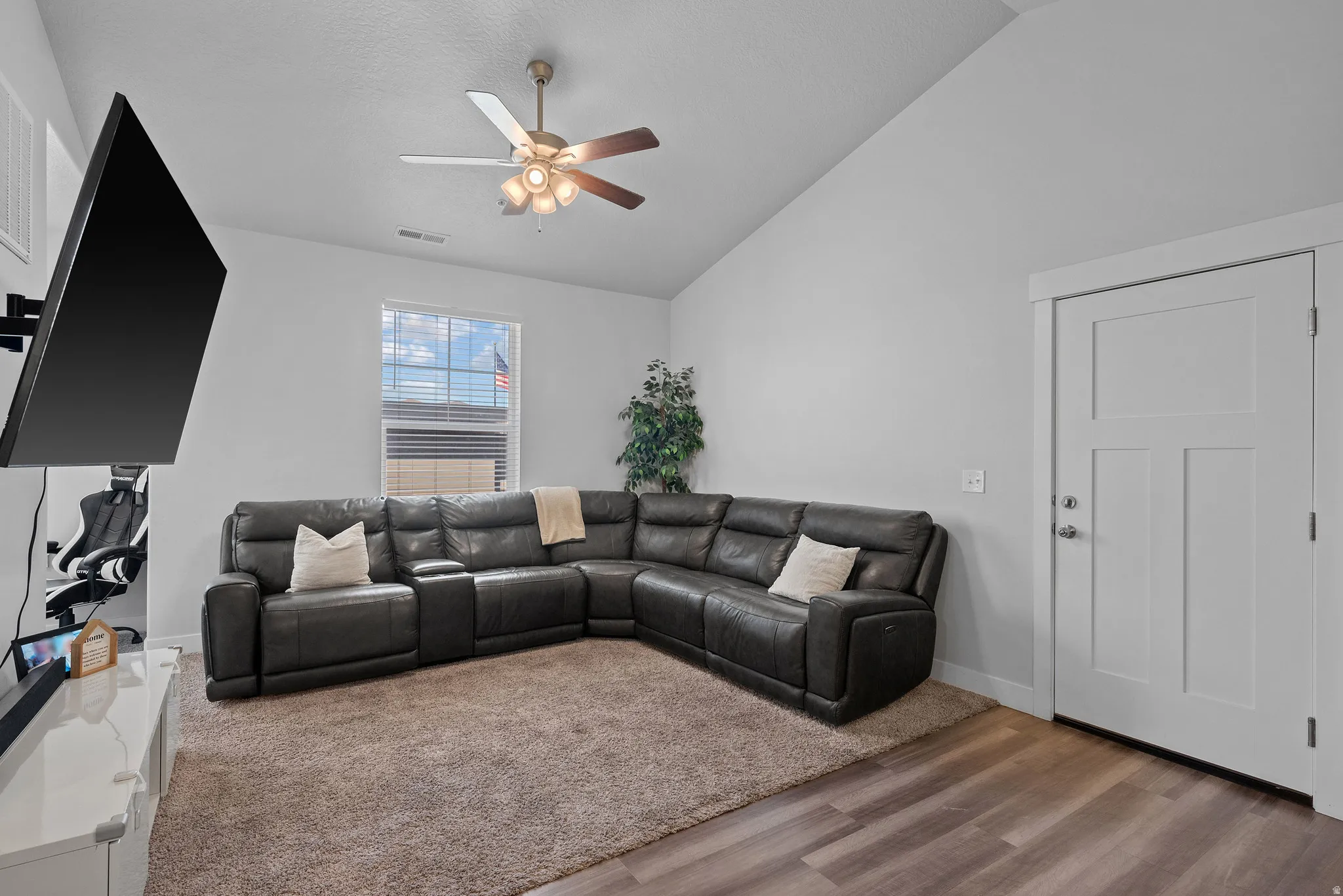 Living room featuring a ceiling fan, wood finished floors, and vaulted ceiling