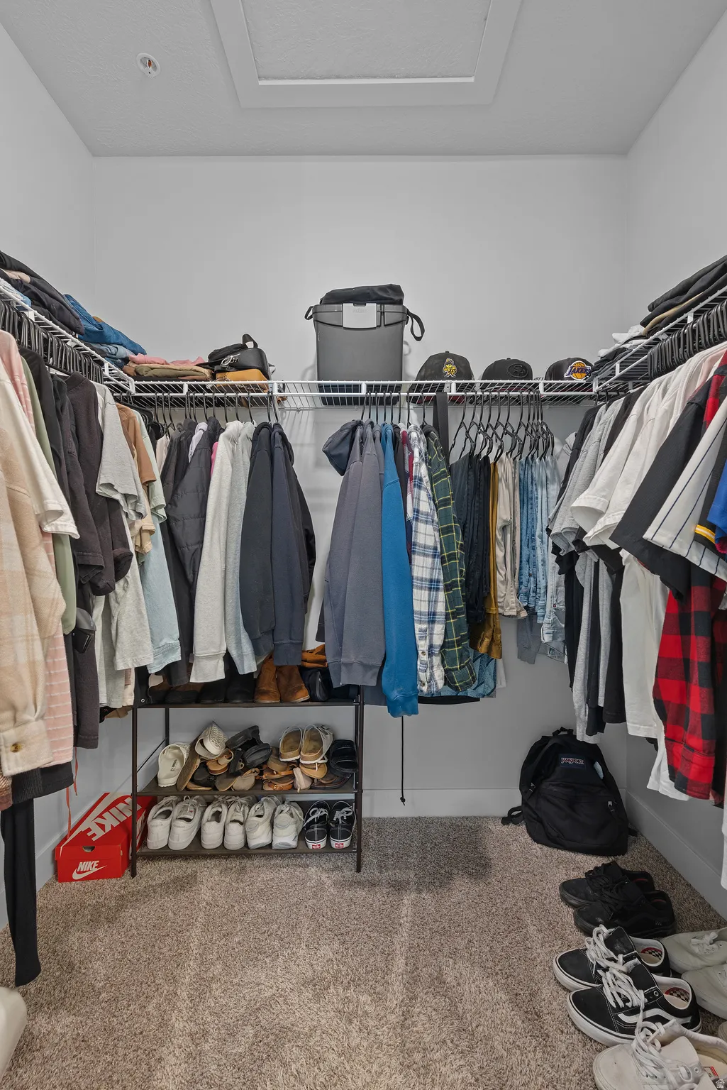 Walk in closet with carpet floors and attic access