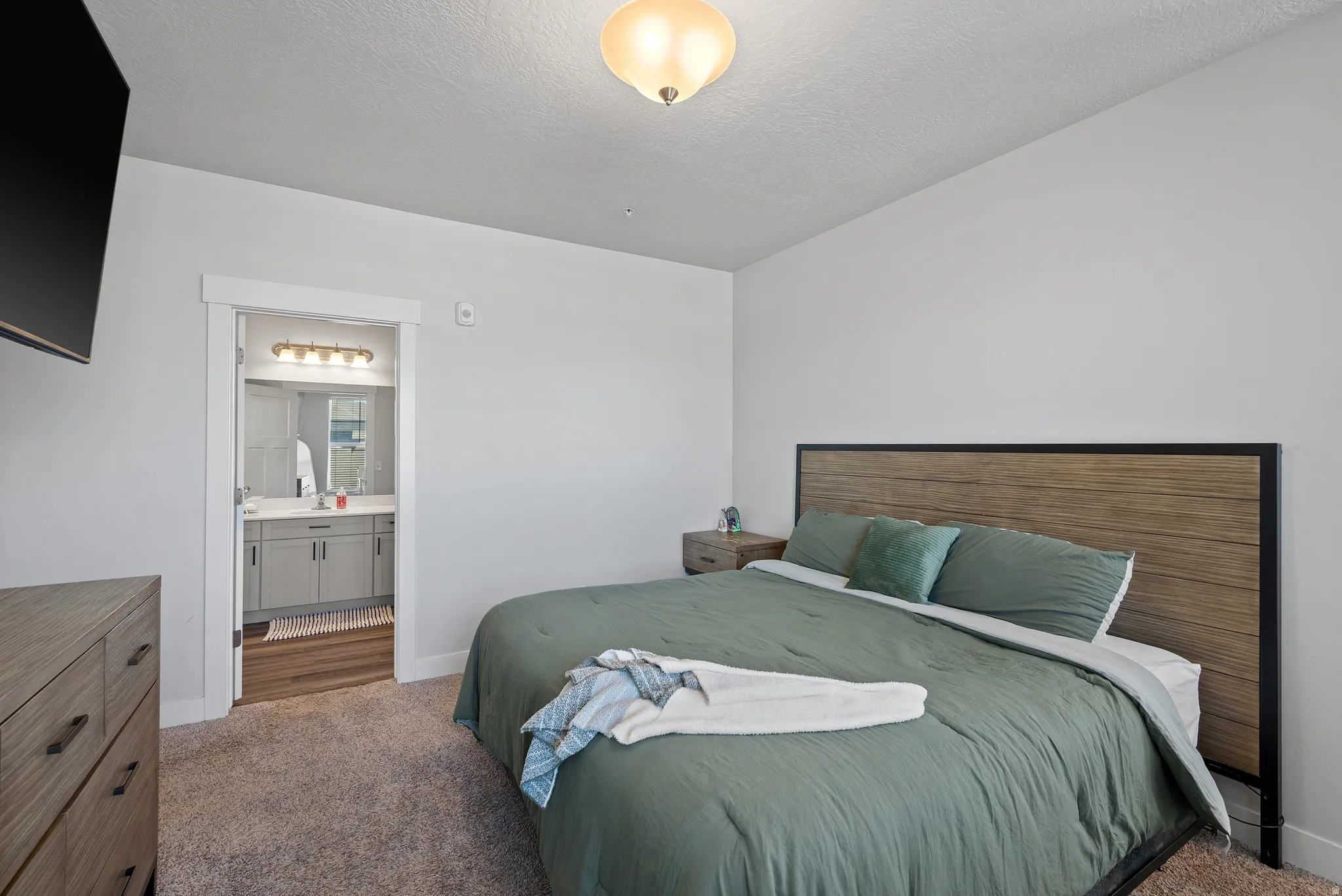 Bedroom featuring dark carpet, a textured ceiling, and connected bathroom