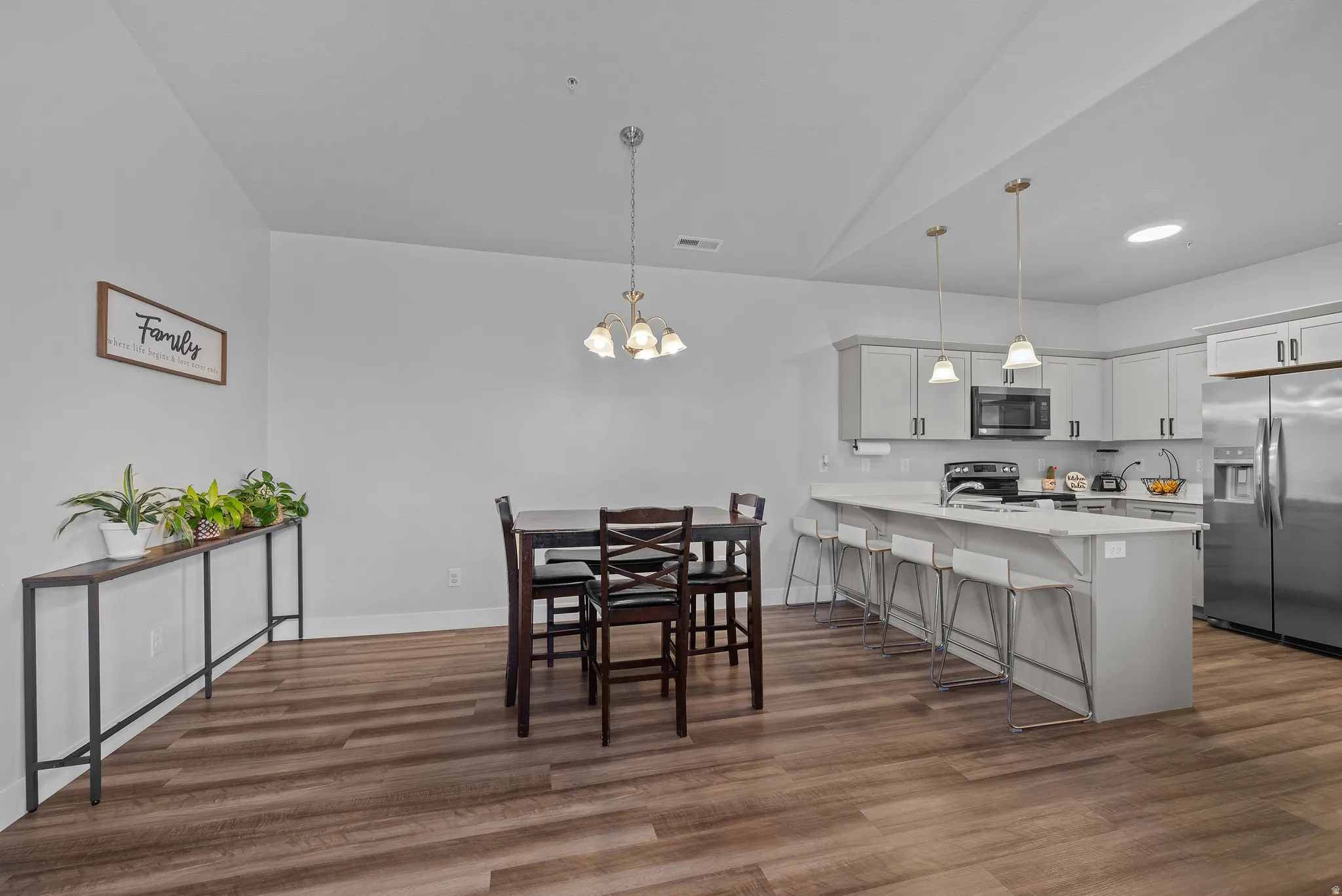 Dining area featuring hanging lights and dark wood-style flooring