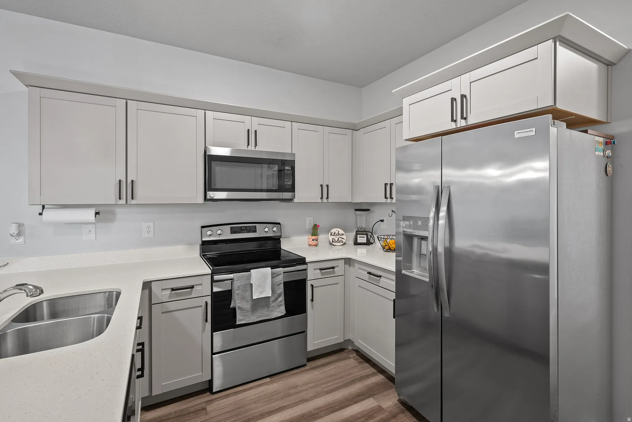 Kitchen featuring stainless steel appliances, dark wood finished floors, and light stone counters