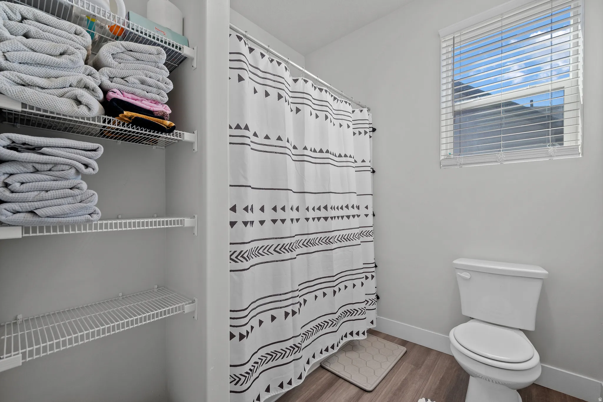 Full bathroom featuring curtained shower and light wood-style floors