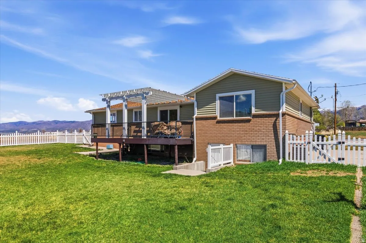 Rear view of house featuring a deck with mountain view, a pergola, a gate, and brick siding