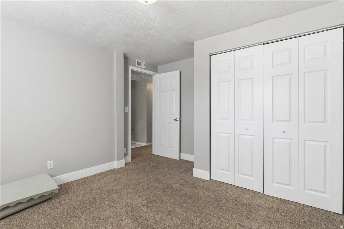 Unfurnished bedroom with carpet flooring, a closet, and a textured ceiling