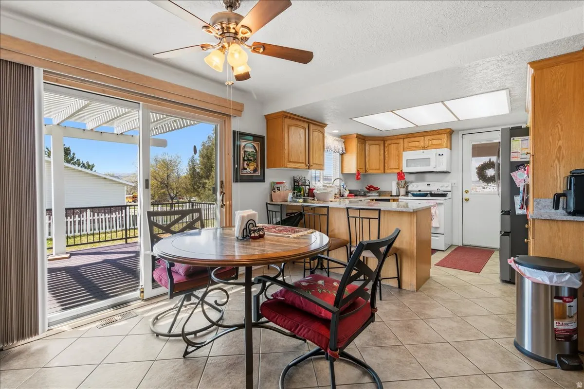 Dining space with a ceiling fan, light tile patterned floors, and a textured ceiling