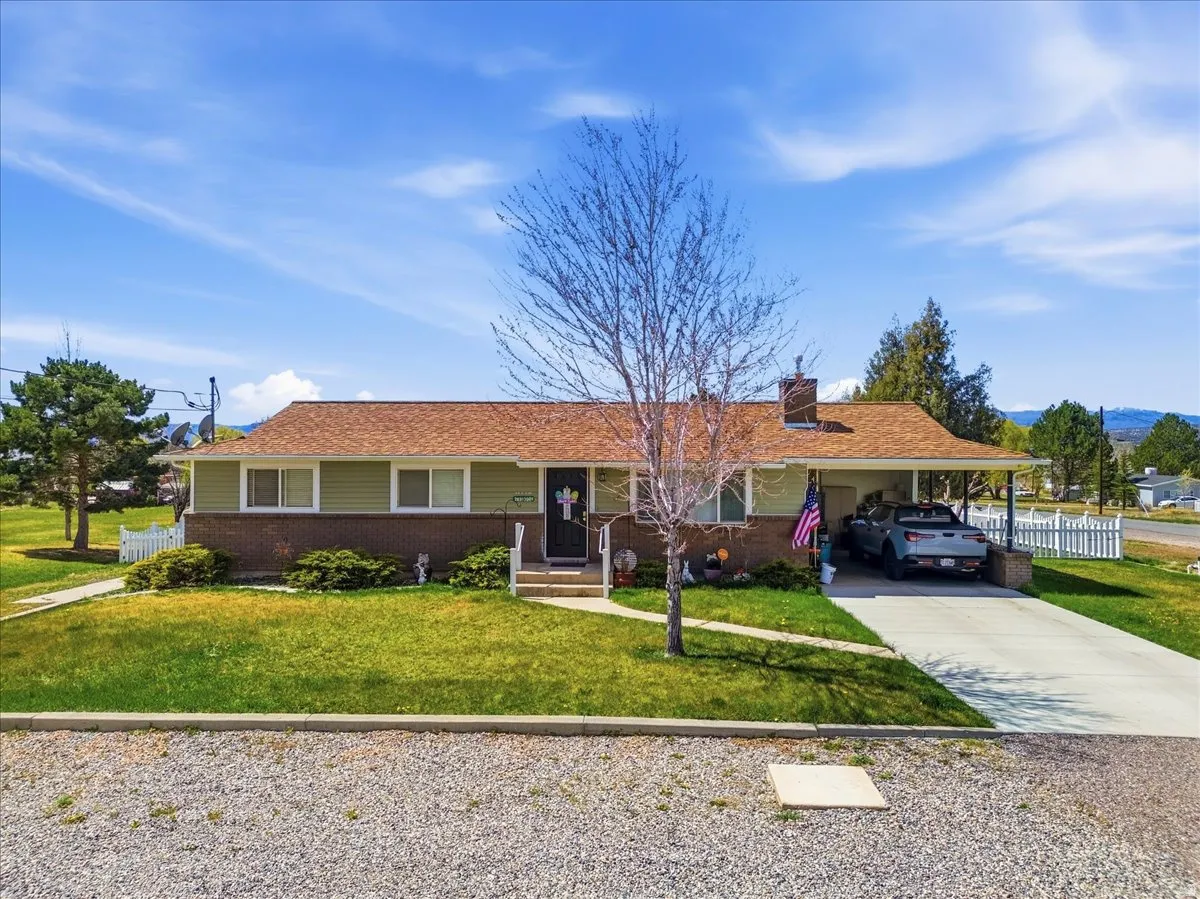 Ranch-style house with a carport, brick siding, concrete driveway, a chimney, and a porch