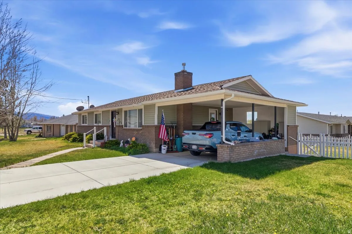 Single story home with a carport, a chimney, brick siding, and driveway