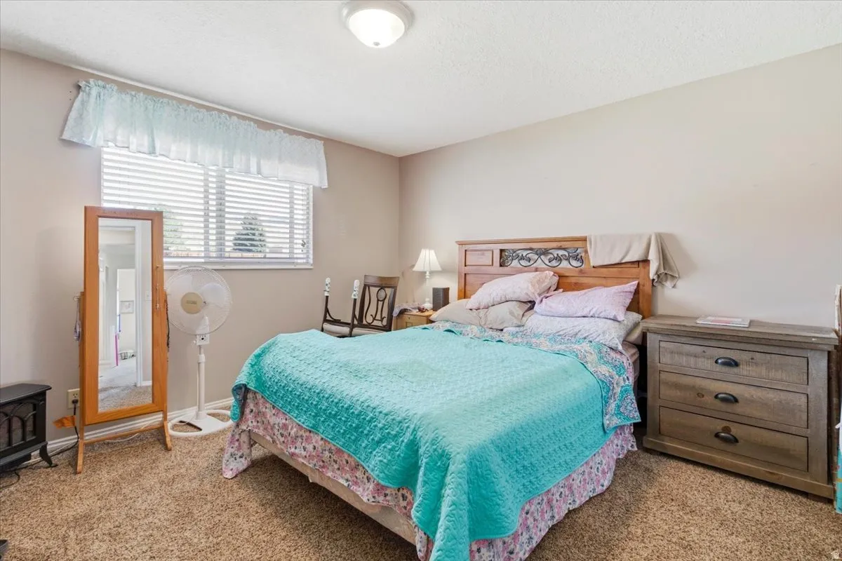 Bedroom with light colored carpet and a textured ceiling