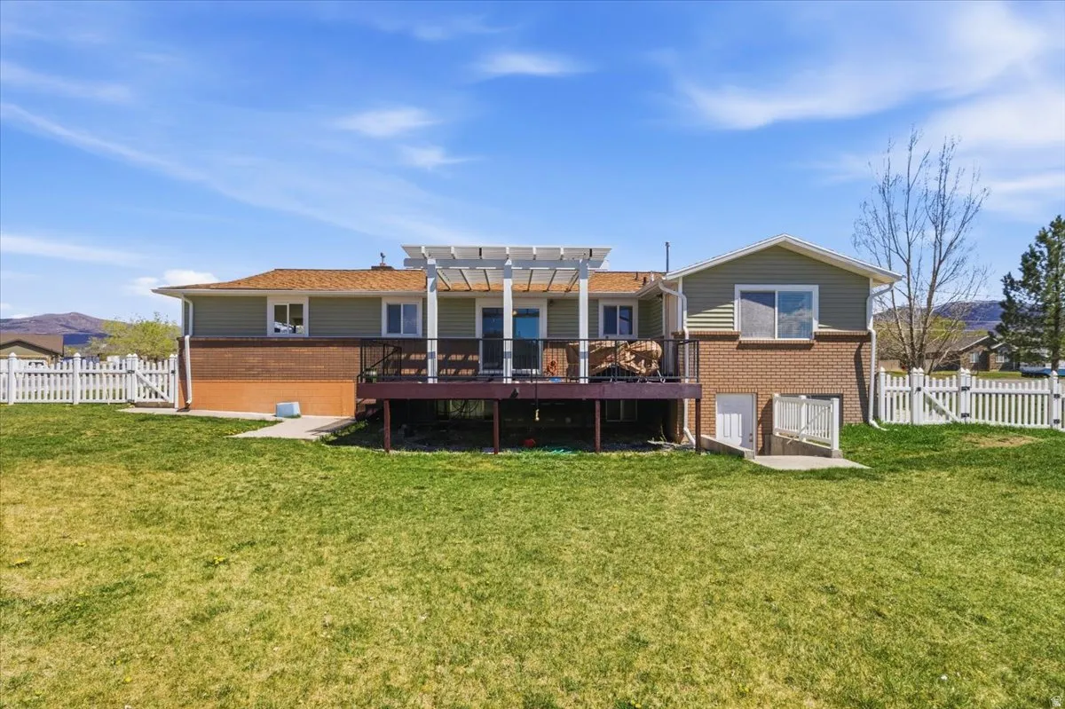 Back of house with a fenced backyard, brick siding, a deck, and a gate