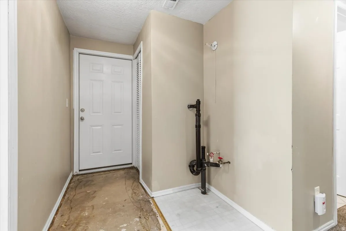 Doorway with a textured ceiling and tile patterned floors