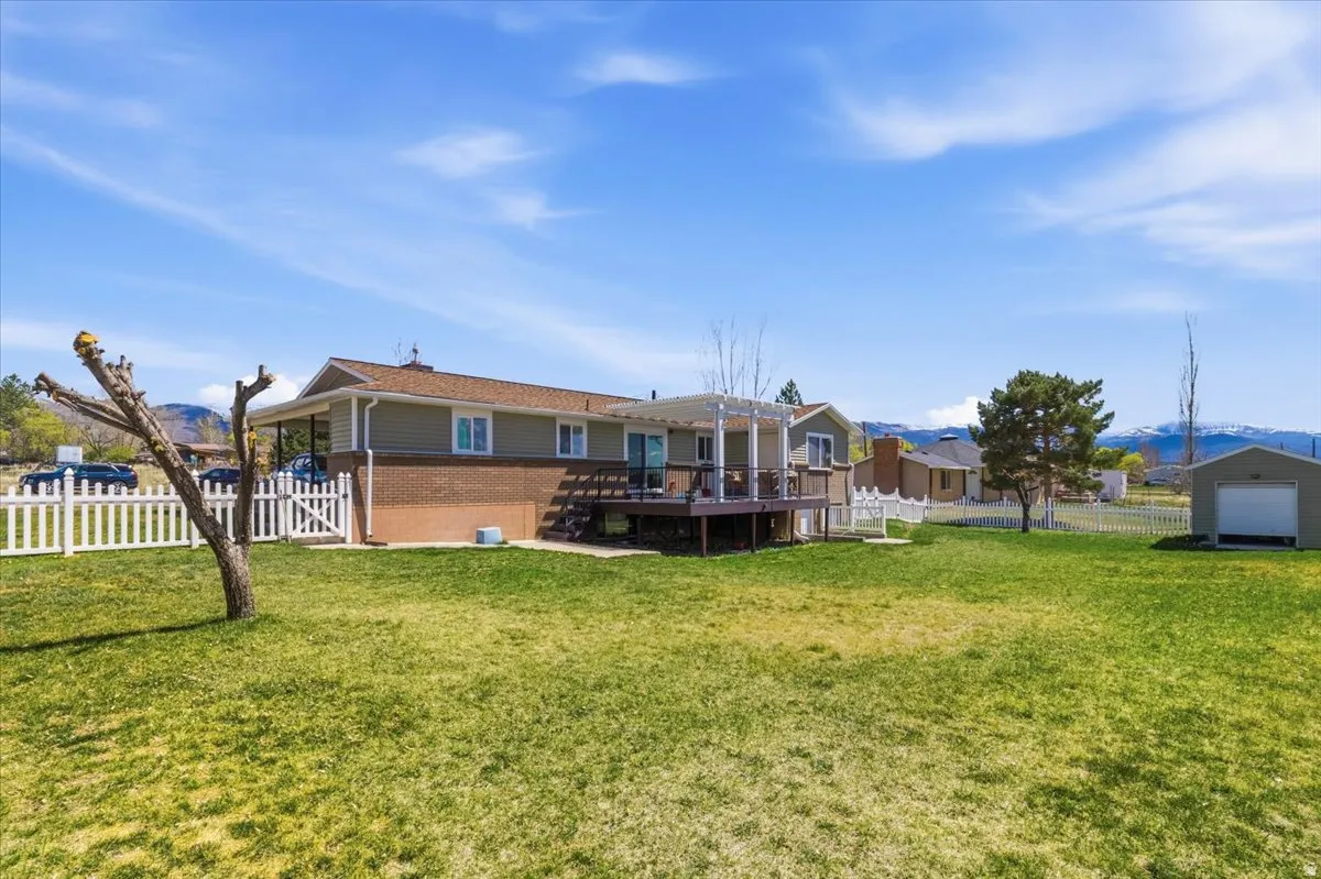 Back of house featuring a deck with mountain view, a fenced backyard, and brick siding