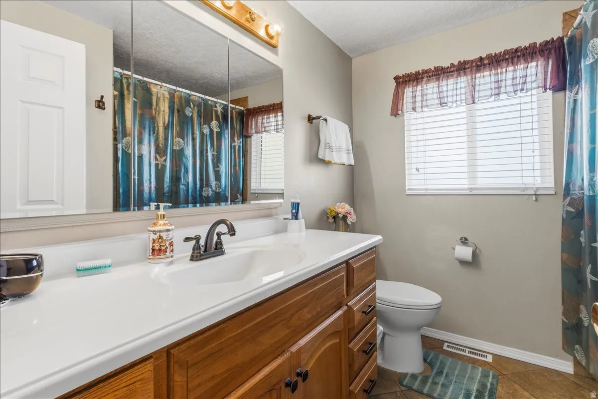 Bathroom featuring vanity, dark tile patterned floors, a shower with shower curtain, and a textured ceiling
