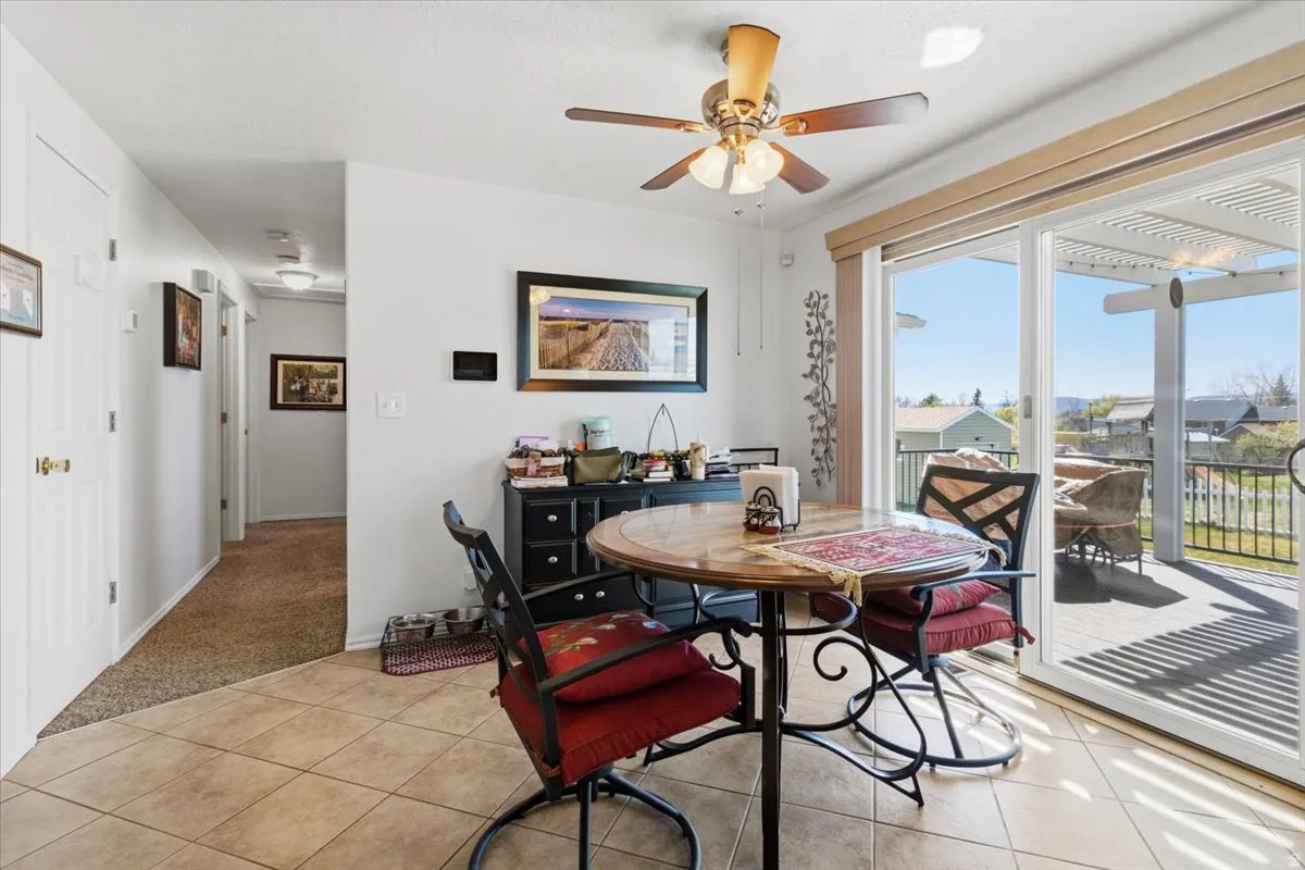 Dining space with a ceiling fan, light carpet, and light tile patterned floors