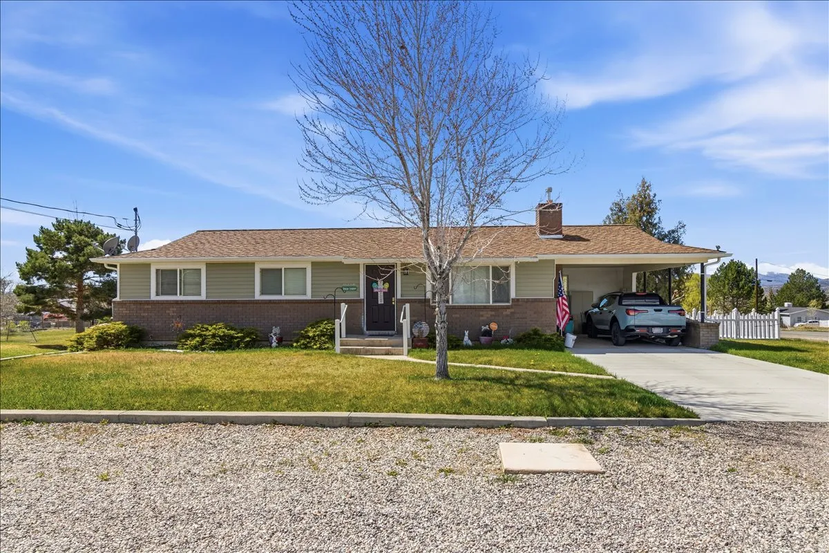 Ranch-style home with driveway, an attached carport, a front lawn, and brick siding