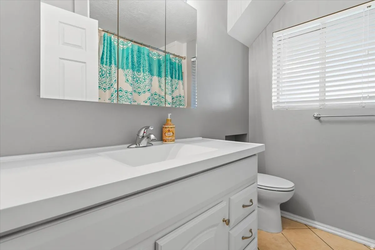 Bathroom with vanity, curtained shower, light tile patterned floors, and a textured ceiling