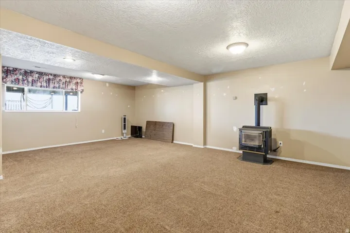 Below grade area with a wood stove, a textured ceiling, and carpet