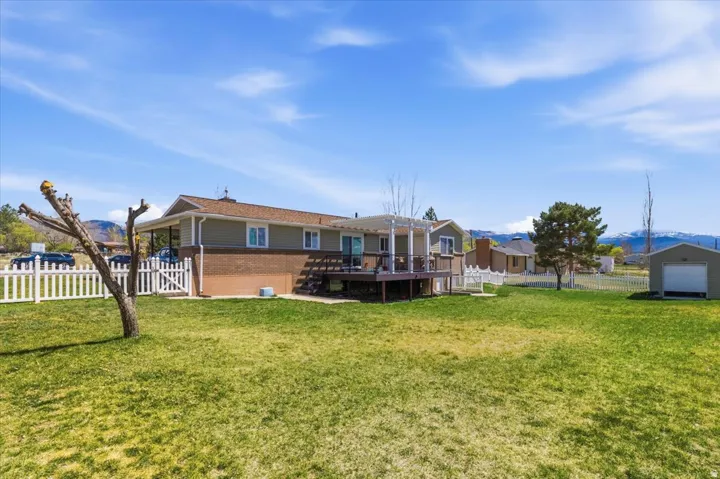 Back of house featuring a deck with mountain view, a fenced backyard, and brick siding