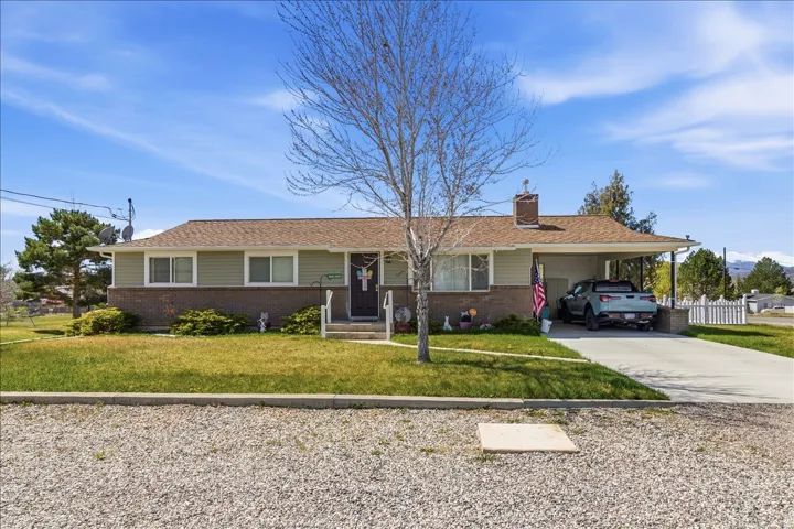 Ranch-style home with driveway, an attached carport, a front lawn, and brick siding