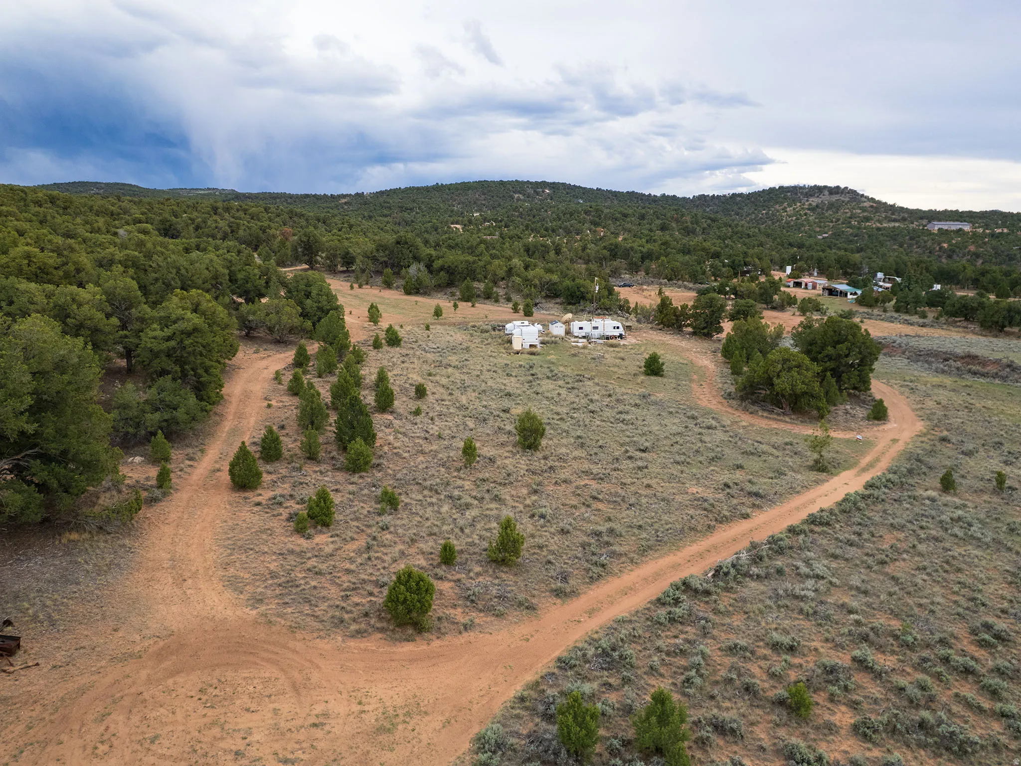 Overview of rural landscape with a heavily wooded area and a mountainous background