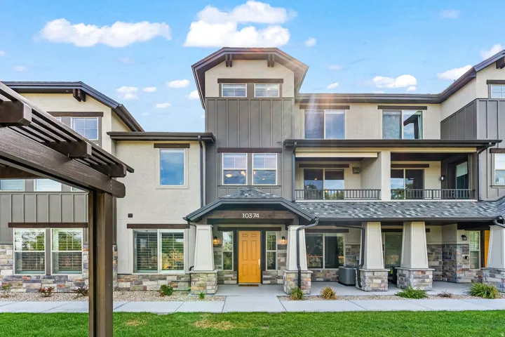 Back of property with stone siding, stucco siding, and a lawn