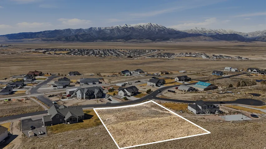 Aerial view of residential area featuring property boundaries highlighted and a mountain backdrop