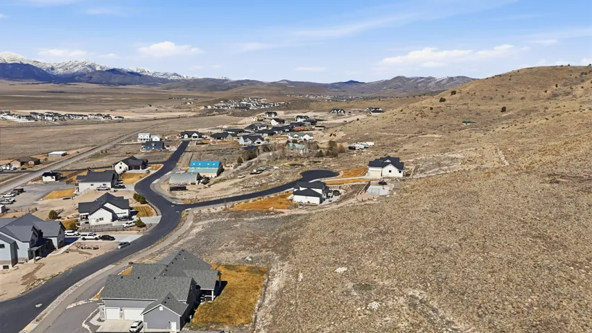 Aerial view of property and surrounding area with nearby suburban area and a mountain backdrop