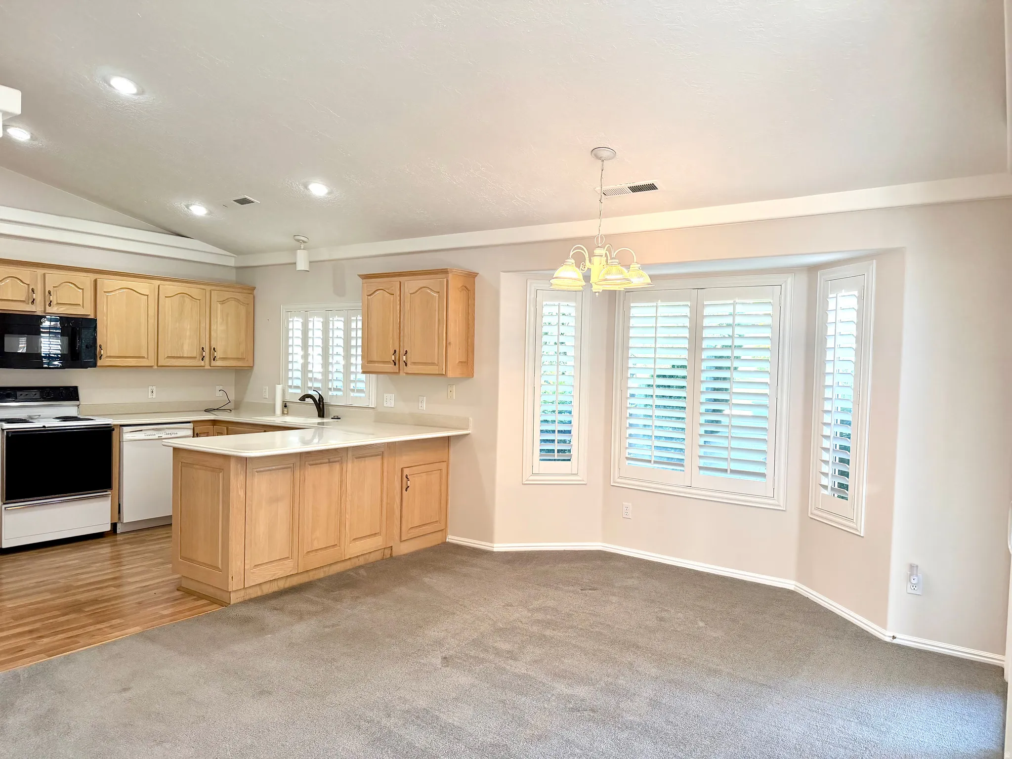 Open-concept kitchen and dining area featuring light-toned cabinetry, light countertops, and integrated appliances