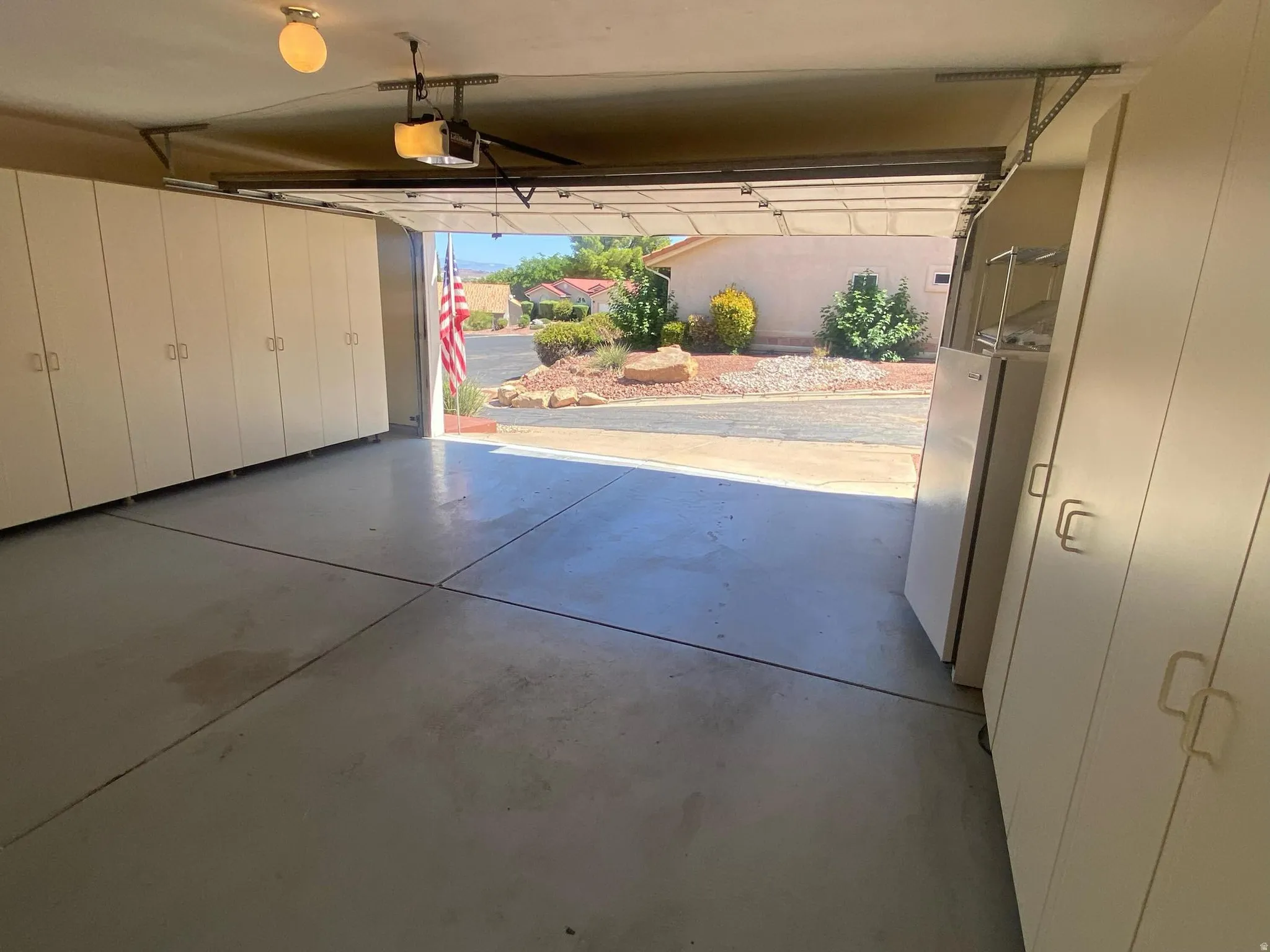 Spacious garage featuring extensive built-in storage cabinetry, a finished concrete floor, and an overhead garage door opener