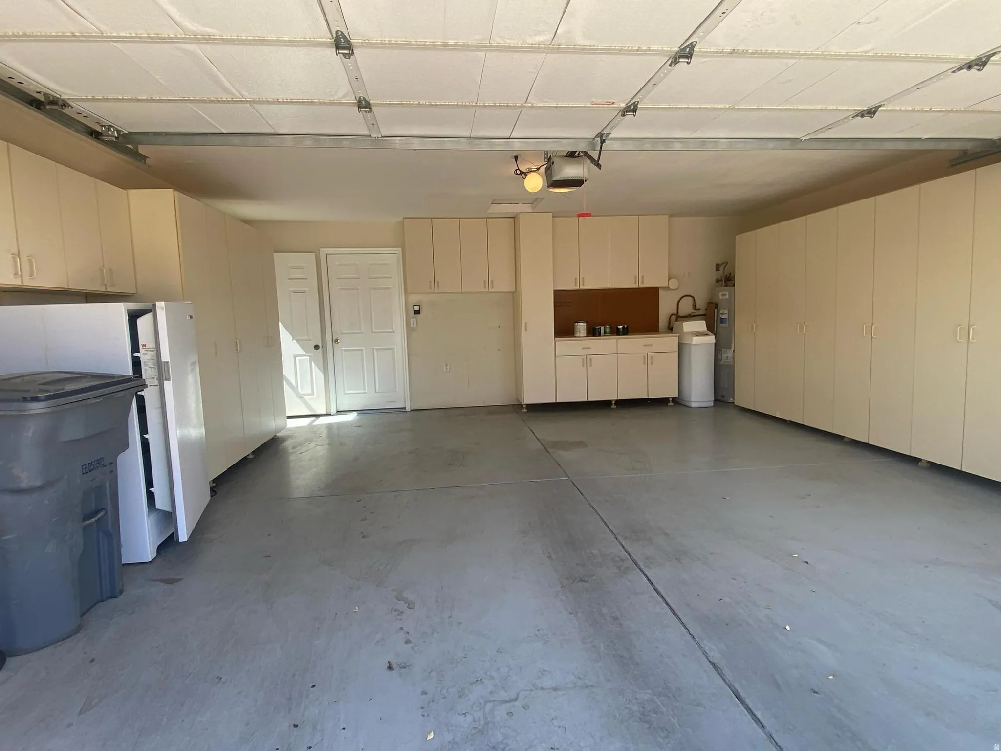 Spacious garage featuring extensive built-in cabinetry, a utility sink, and durable concrete flooring