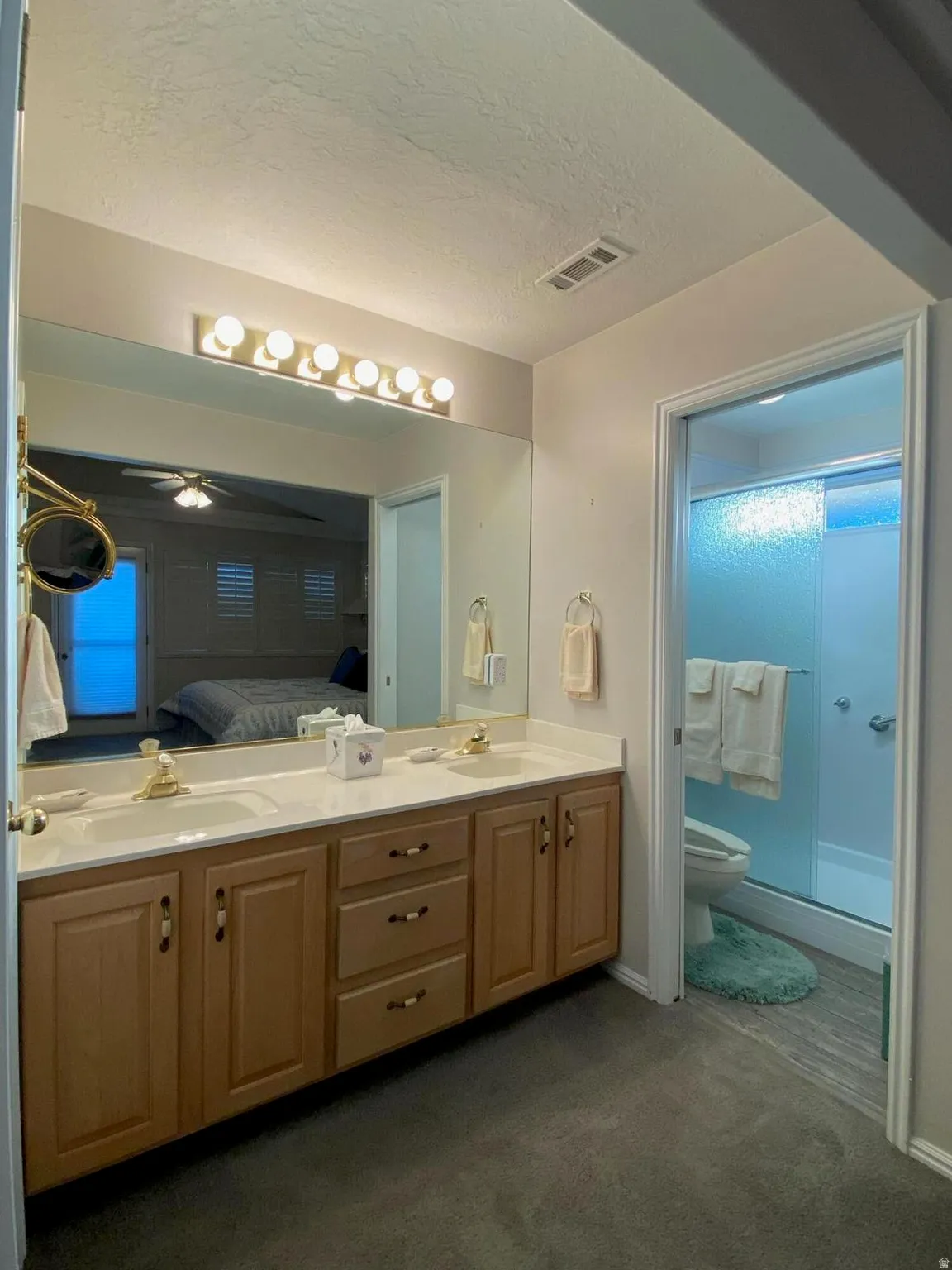 Double vanity featuring light wood-finish cabinetry, dual sinks, and a large wall-mounted mirror